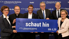 Verantwortliche des Ökumenischen Kirchentags 2021 mit einer Tafel „Schaut hin“s