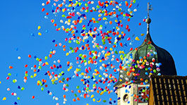 Bunte Luftballons vor einem Kirchturm
