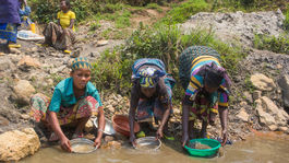 Frauen im Kongo waschen Zinnerz aus Gestein
