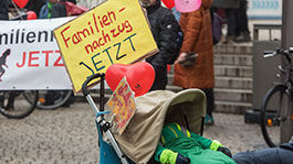 Kinderwagen mit Schild „Familiennachzug jetzt“ bei einer Demo in Berlin