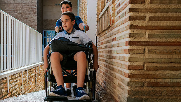 Junge im Rollstuhl auf einer Rampe zur Schule