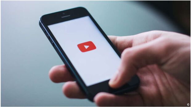 Smartphone mit YouTube Zeichen auf weißem Bildschirm