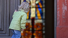 Kleines Mädchen an der Kirchentür schaut in die Kirche