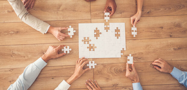 Puzzleteile die von Händen zusammen gelegt werden - URAKs