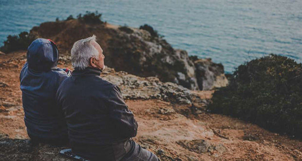 Ein älteres Paar sitzt auf Steinen am Meer
