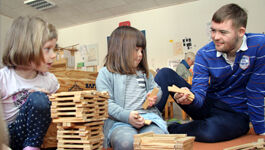 zwei Mädchen mit Erzieher im Kindergarten