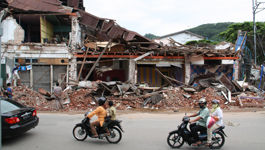 Motorradfahrer vor eingestürzten Häusern