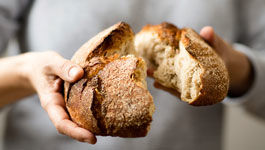 Hände halten ein gebrochenes Brot