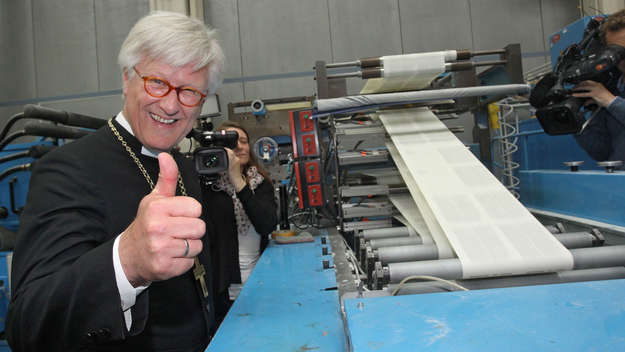 EKD-Ratsvorsitzender Heinrich bedford-Strohm hebt den Daumen vor den laufenden Druckmaschinen in der Druckerei C.H.Beck zum Andruck der Lutherbibel 2017