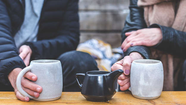 Zwei Personen sitzen nebeneinander und trinken eine Tasse Tee