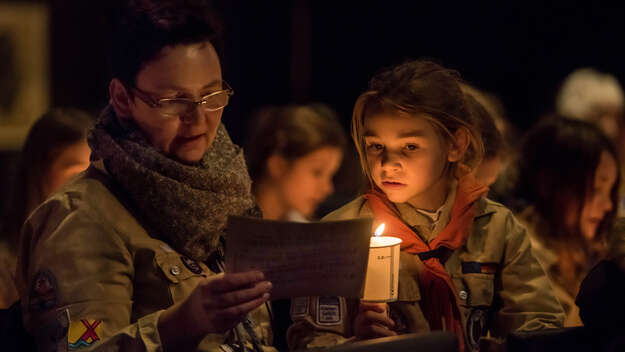 Pfadfinder halten eine brennende Kerze