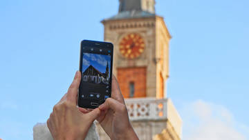 Smartphone vor einen Kirchturm gehalten, auf dem Dsiplay die Kirche