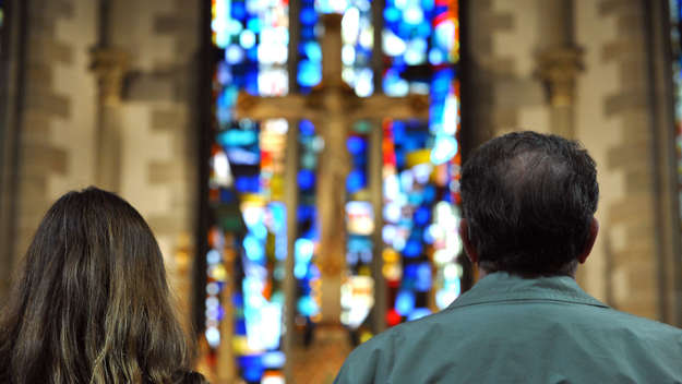 Ein Mann und eine Frau stehen vor dem Kreuz in einer Kirche