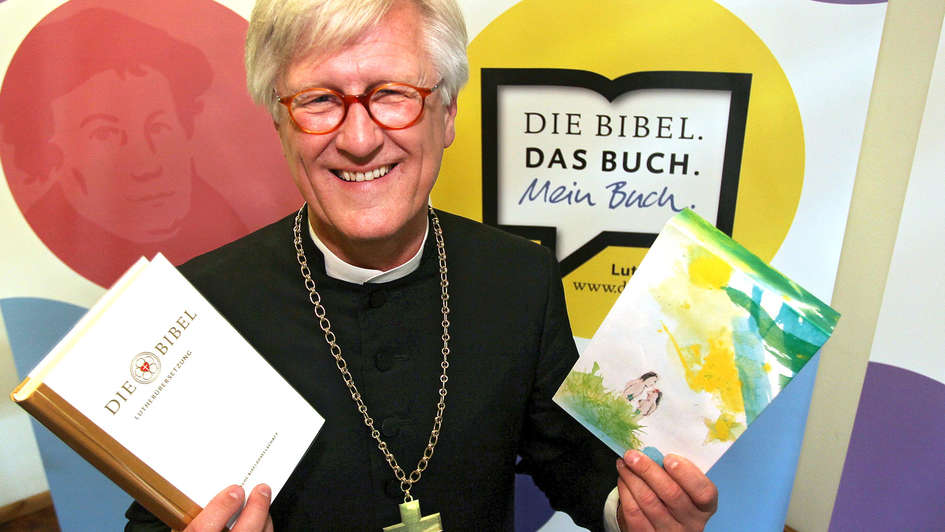 Heinrich Bedford-Strohm hält zwei Ausgaben der Lutherbibel