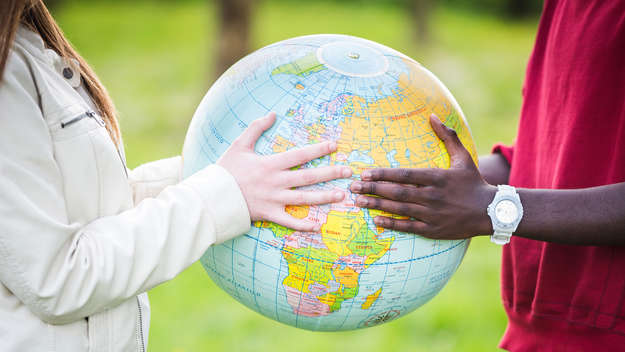 Eine Frau und Mann multiethnischer Herkunft halten einen Globus in den Händen.