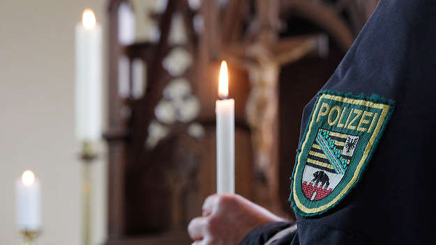 Ein Polizist hält in der Polizeikirche Sachsen-Anhalts in Dessau eine Kerze in der Hand.