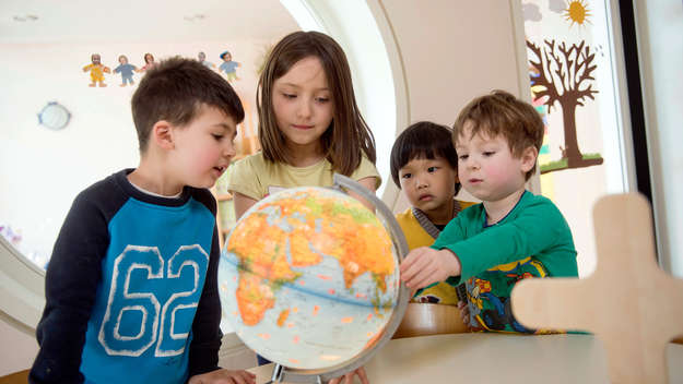 Kinder spielen mit einem Globus im evangelischen Kindergarten 'Brummkreisel' im westfälischen Espelkamp.