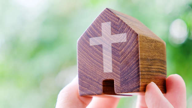 Hand mit Kirche aus Holz.