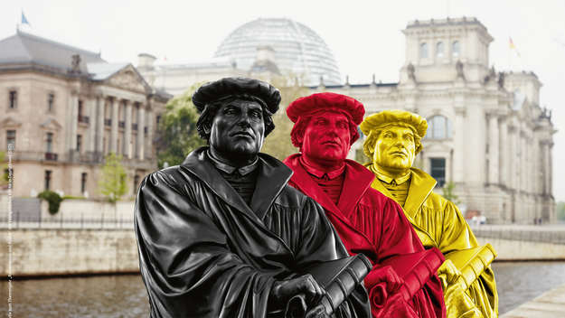 Lutherstatuen in schwarz, rot und gold vor dem Reichstag.