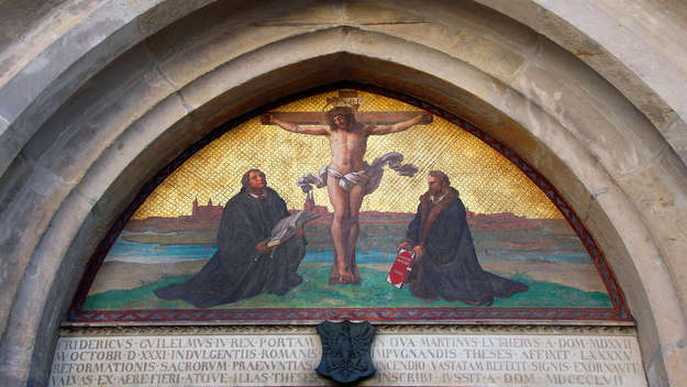 Darstellung des gekreuzigten Jesus mit den Reformatoren Martin Luther (1483-1546, li.) und Philipp Melanchthon (1497-1560) über der 'Thesentür' der Wittenberger Schlosskirche.