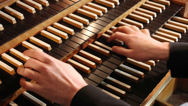 Hände eines Organisten auf den Tasten einer Orgel.