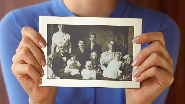 Nahaufnahme einer Frau, die ein altes Familienfoto in den Händen hält.