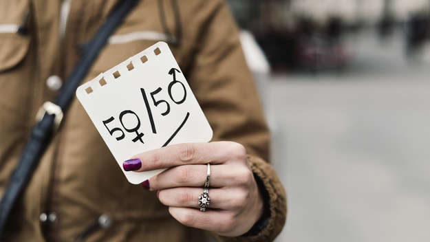 Frau mit Zettel in der Hand auf dem '50/50' steht.