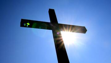 Kreuz im Gegenlicht vor blauem Himmel
