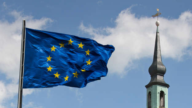 Eine europäische Flagge weht vor einer Kirche.