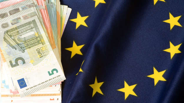 Geldscheine liegen auf einer EU-Flagge.