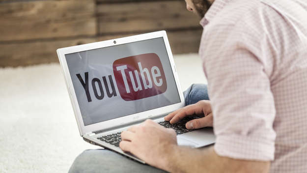 Mann mit einem Laptop, auf dem das Youtube-Logo zu sehen ist.
