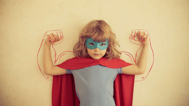 Ein Mädchen posiert im Superheldenkostüm.