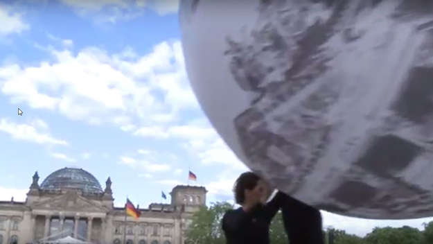 Menschen einen Weltkugel-Ball vor dem Berliner Reichstag