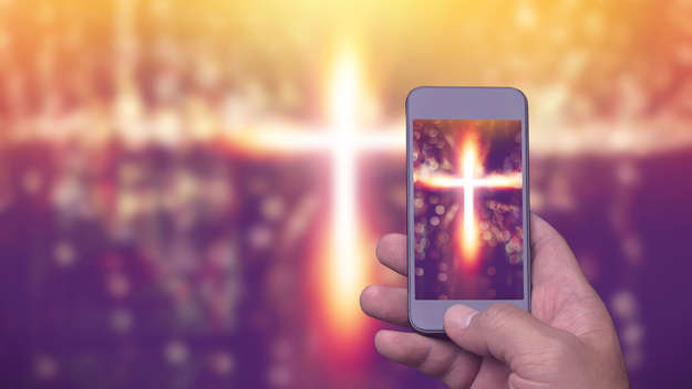 Mann macht mit seinem Handy Foto von einem Kreuz