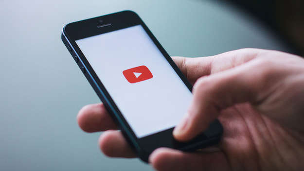 Eine Hand hält ein Smartphone mit Youtube-Logo auf dem Bildschirm