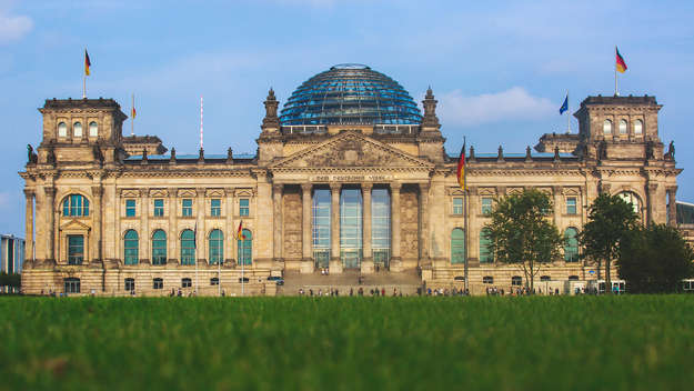 Blick über eine grüne Wiese auf das Reichstagsgebäude in Berlin