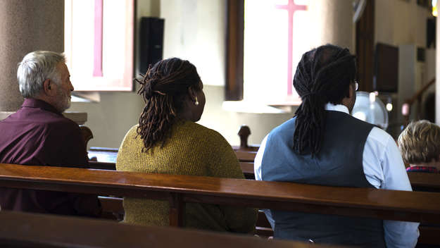 Männer und Frauen sitzen in einer Kirchenbank