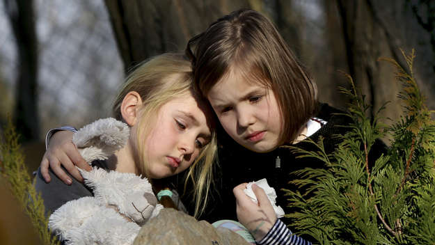 Zwei Mädchen sitzen am Grab ihres Haustiers und trauern