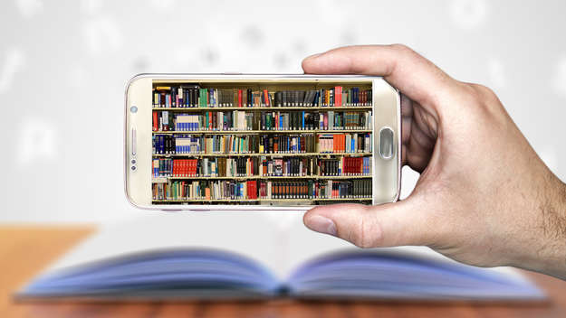 Einen Hand hält ein Smartphone mit Bücherregalen auf dem Display