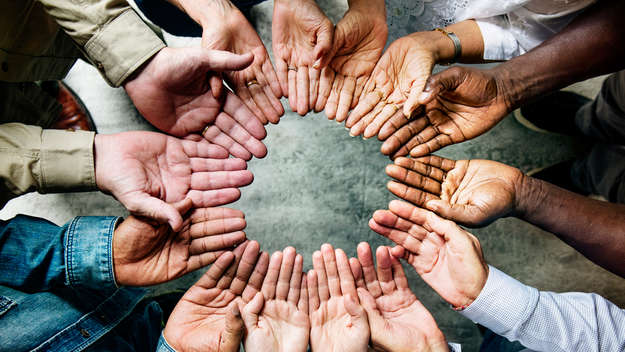 Nahaufnahmen von Händen einer multikulturellen Gruppe, die einen Kreis bilden.