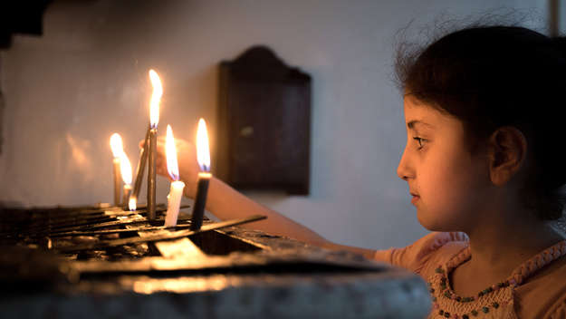 Ein Mädchen zündet eine Kerze an beim Gottesdienst der syrisch-orthodoxen Gemeinde 'Marian al-Adra' in Qamischli in Syrien