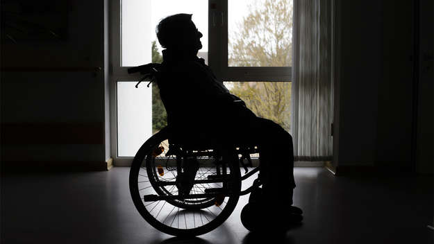 Alter Mann im Rollstuhl im Gegenlicht, Symbolbild