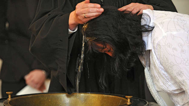 Pfarrer tauft eine Frau
