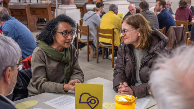 Menschen sitzen gemeinsam am Tisch beim Dialogforum in der Friedenskirche Ludwigsburg