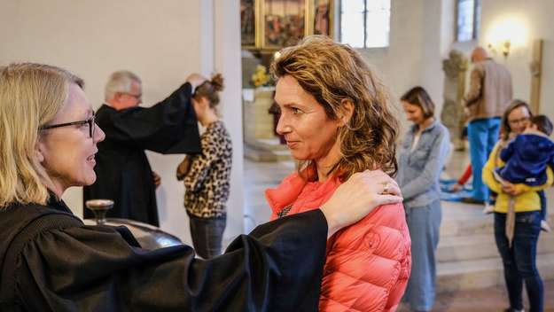 Eine Pfarrerin segnet eine Gottesdienstbesucherin
