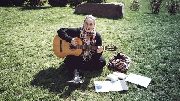 Pfarrerin Anneke Peereboom singt mit ihrer Gitarre auf einer Wiese