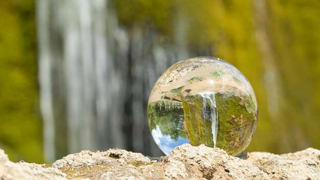 Eine Glaskugel vor einem Wasserfall