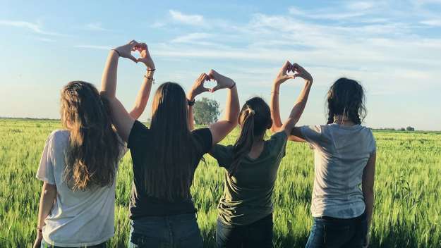 Vier Mädchen formen Herzen mit ihren Händen
