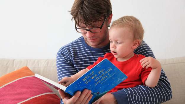 Vater liest Sohn aus einem Buch vor