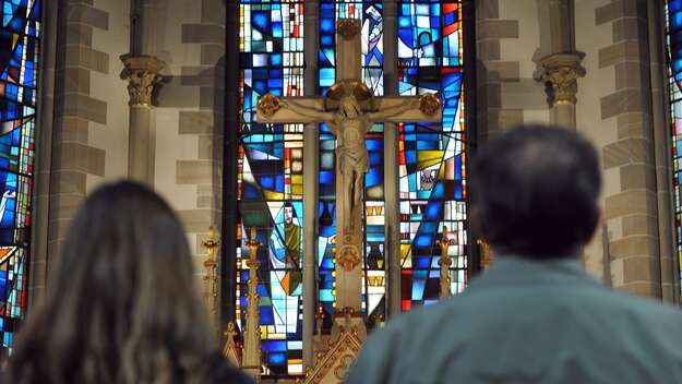Frau und Mann stehen in der Gartenkirche St. Marien in Hannover vor dem Kreuz